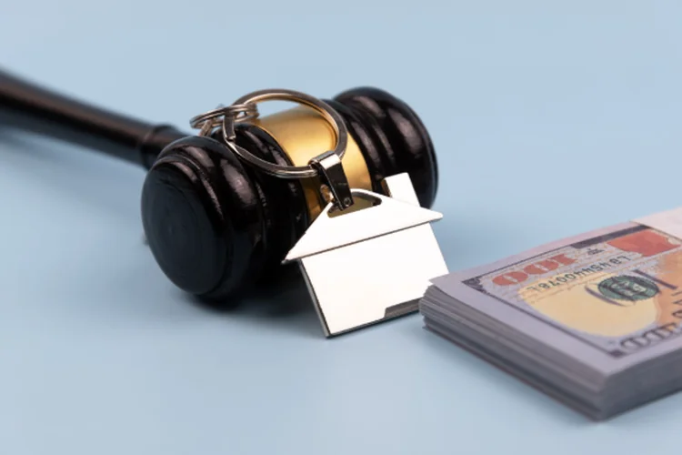 Gavel and model house blue background with money.