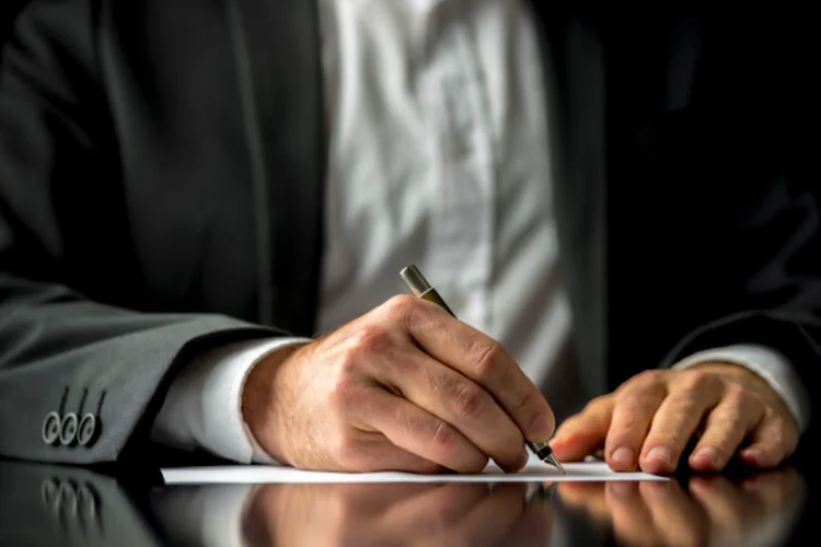a man in a suit is writing a letter 