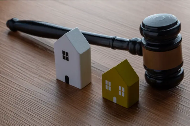 a gavel and two miniature wooden houses on the table