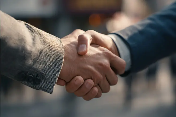  Close up of two people shaking hands in a formal agreement or partnership.