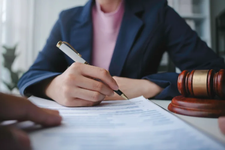 A lawyer is signing a last will and testament during a meeting with a client.