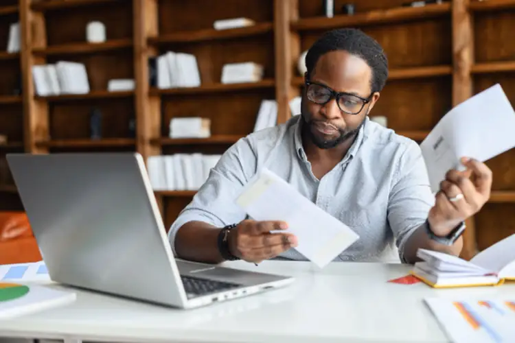 Worried African-American looking through correspondence. 