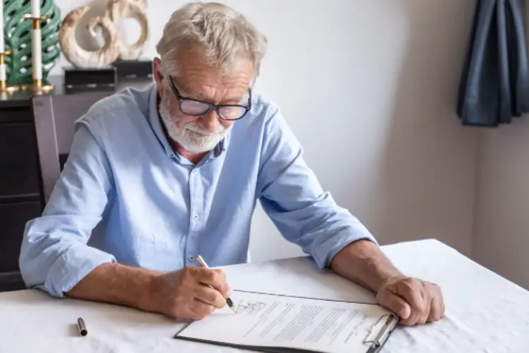 a senior man examines and signs a will 